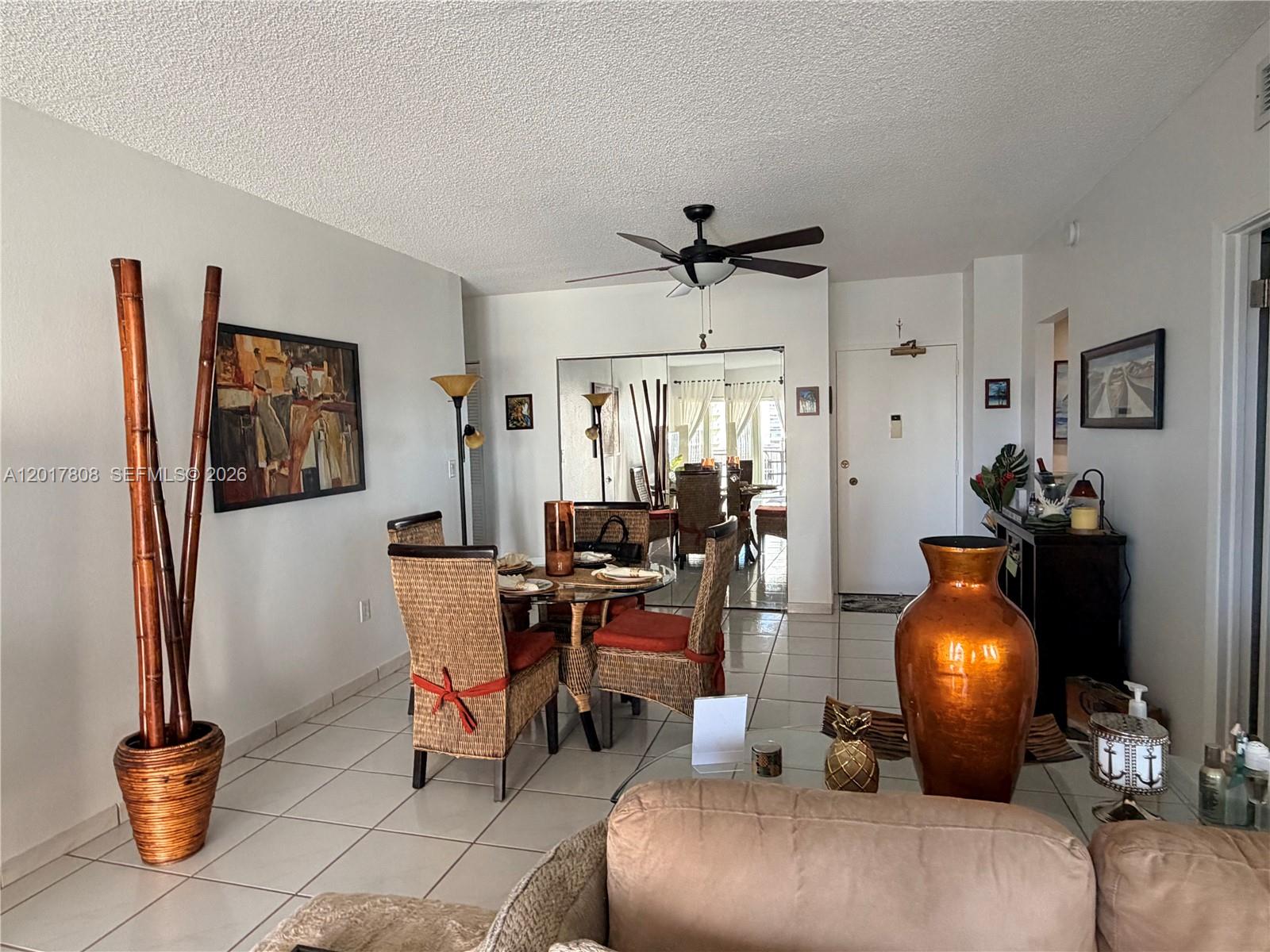 A dining area with wicker chairs and a glass table sits near a living room — 1950 S Ocean Dr # 4B, Hallandale Beach FL 33009, HALLANDALE BEACH, FL