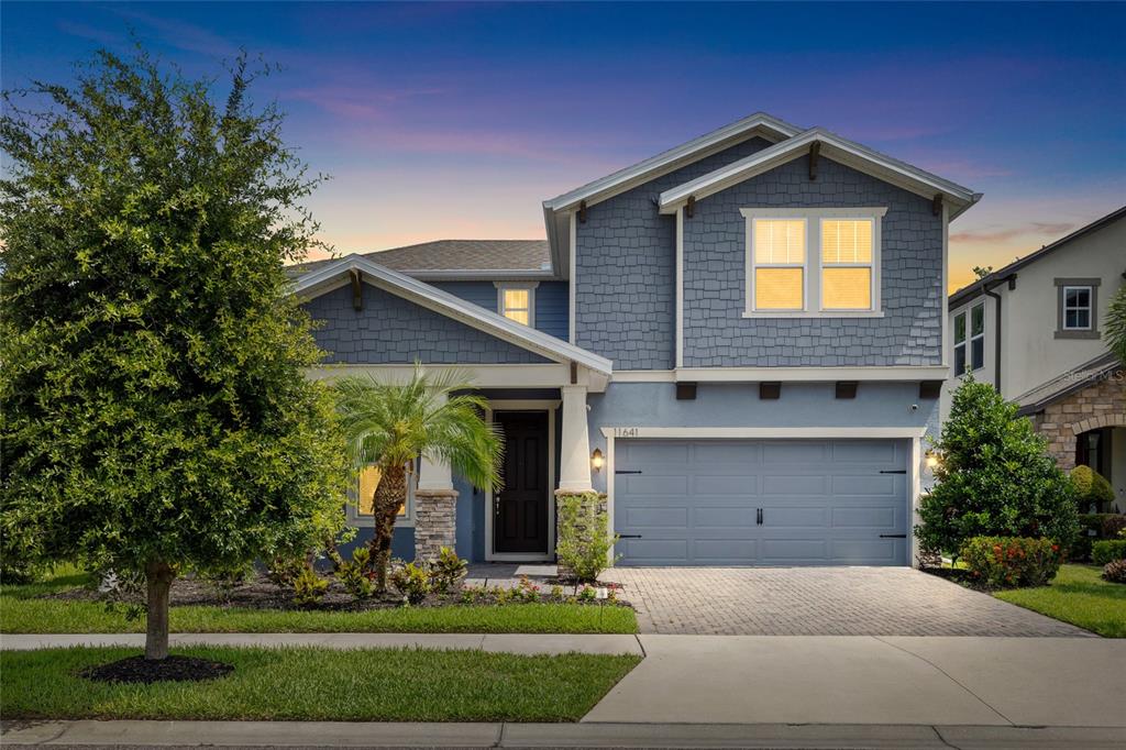 A two-story blue house with a shingled exterior, a two-car garage, and a front porch — 11641 SWEET TANGERINE LANE, TAMPA, FL