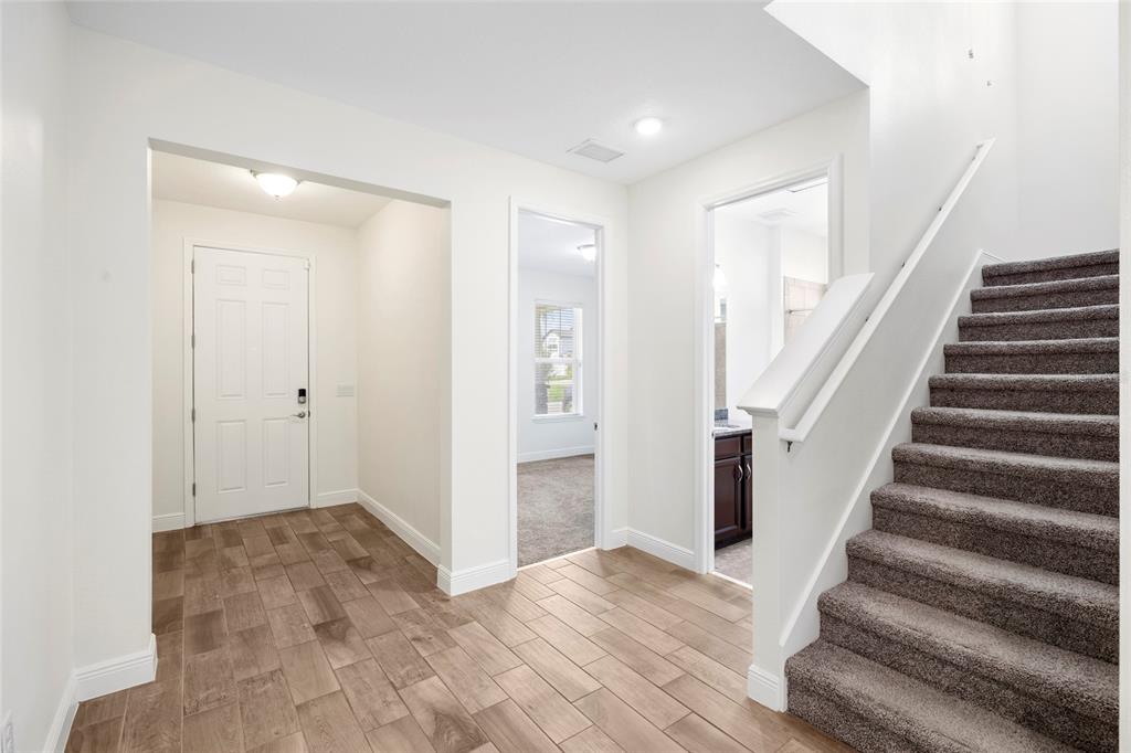 An entryway features wood-look tile flooring, a carpeted staircase, and two doorways leading to rooms — 11641 SWEET TANGERINE LANE, TAMPA, FL