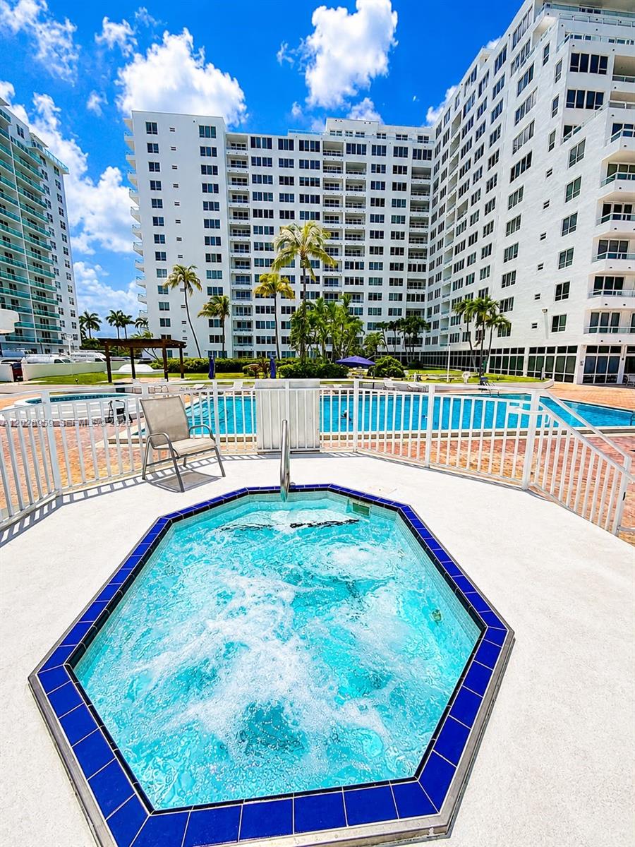 A hot tub with blue tile trim sits on a patio overlooking a swimming pool — 5005 Collins Ave # 616, Miami Beach FL 33140, MIAMI BEACH, FL