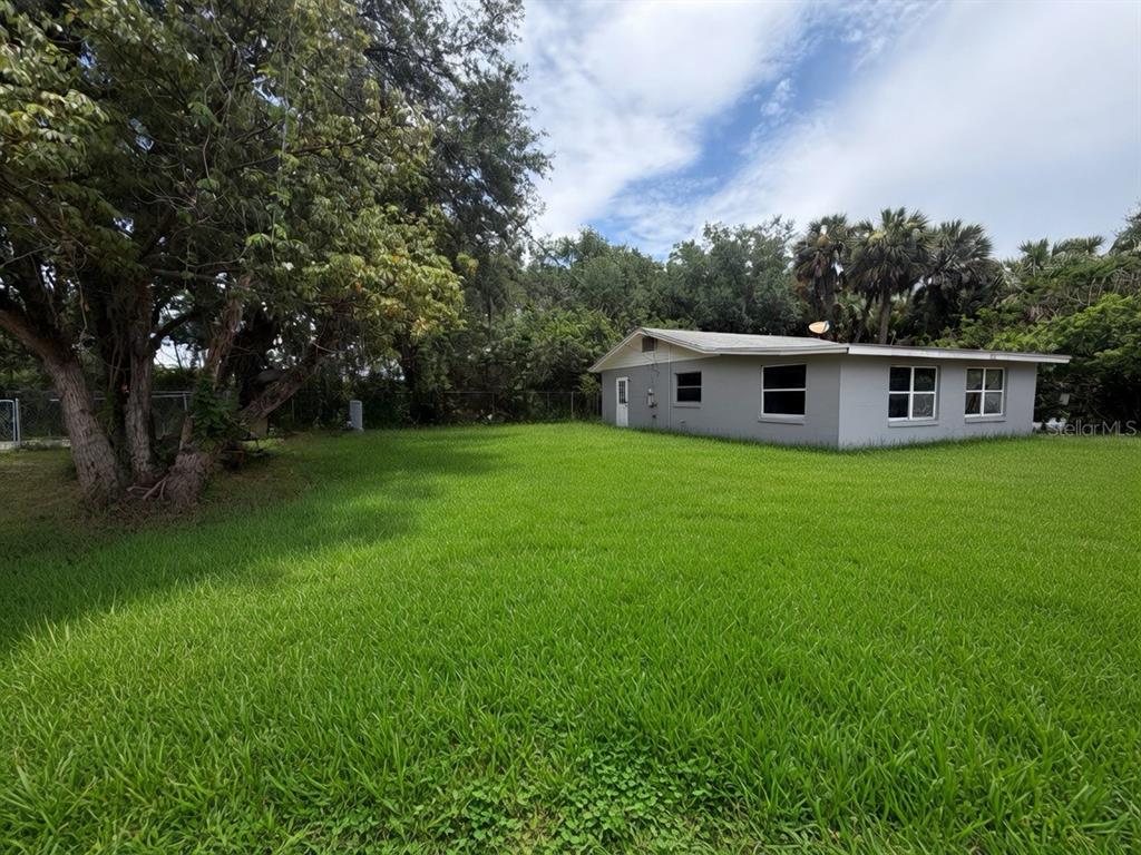 A gray single-story house sits on a large, grassy lawn surrounded by mature trees — 3312 W 5TH STREET, SANFORD, FL