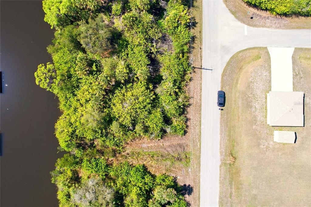 An aerial view shows a wooded lot bordering a body of water next to a road — 594 MCDILL DRIVE, PORT CHARLOTTE, FL