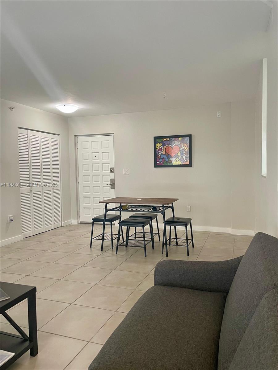 A living and dining area features tile flooring, a grey sofa, and a small dining set — 700 NE 63rd St # D203, Miami FL 33138, MIAMI, FL