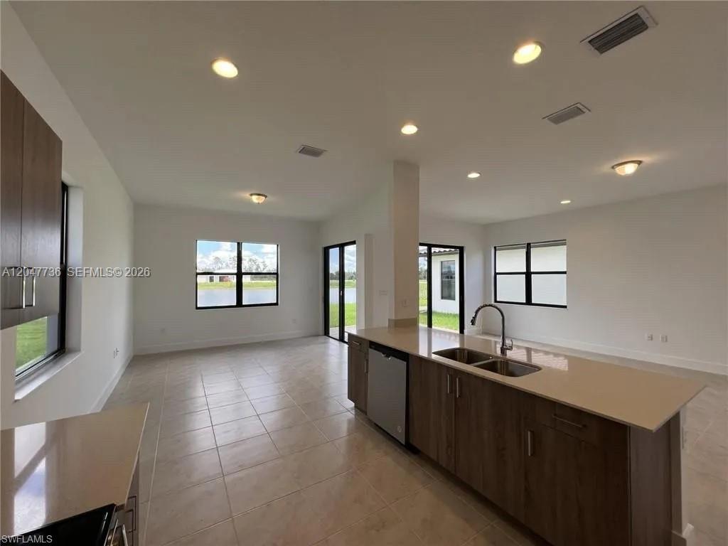 A modern kitchen with wood cabinets and a quartz island overlooks an open living area — 5645 Cerva Lane # 5645, Ave Maria FL 34142, AVE MARIA, FL