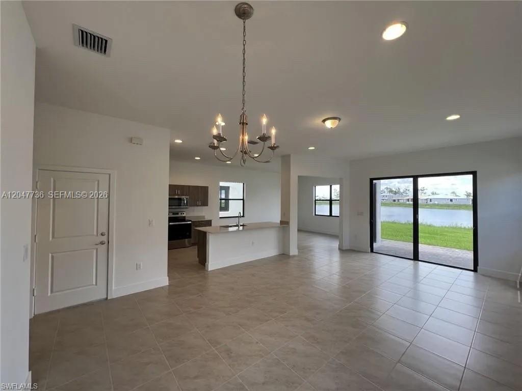 An open-concept living area features tile floors, a kitchen island, and sliding glass doors — 5645 Cerva Lane # 5645, Ave Maria FL 34142, AVE MARIA, FL