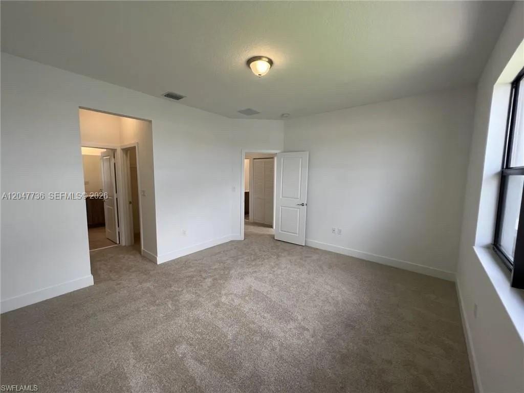 This bedroom features beige carpeting, white walls, a ceiling light fixture, and two doorways — 5645 Cerva Lane # 5645, Ave Maria FL 34142, AVE MARIA, FL