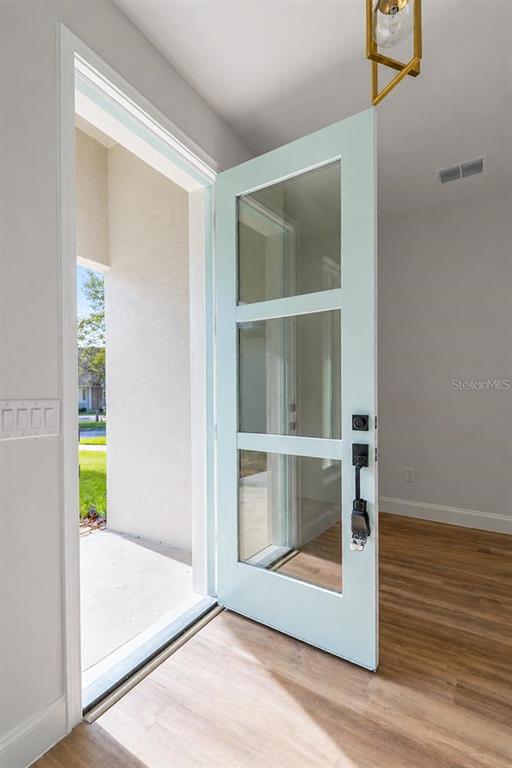A light blue front door with three glass panels opens into a room with wood flooring — 14 RENSHAW DRIVE, PALM COAST, FL