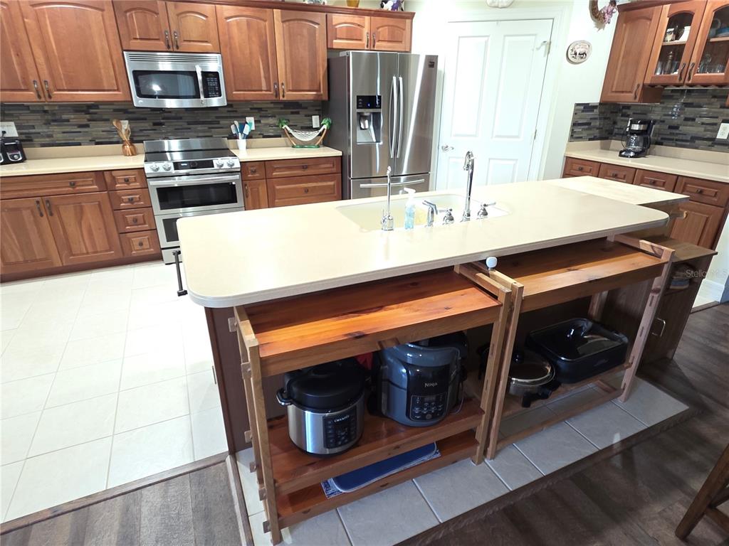 A kitchen features wood cabinets, stainless steel appliances, a central island, and a tile floor — 8152 SOUTHERN PINES DRIVE, BROOKSVILLE, FL