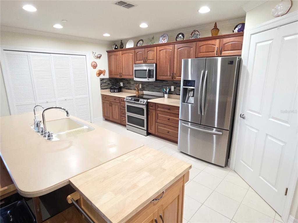 A kitchen features wood cabinets, stainless steel appliances, a large island, and tile flooring — 8152 SOUTHERN PINES DRIVE, BROOKSVILLE, FL