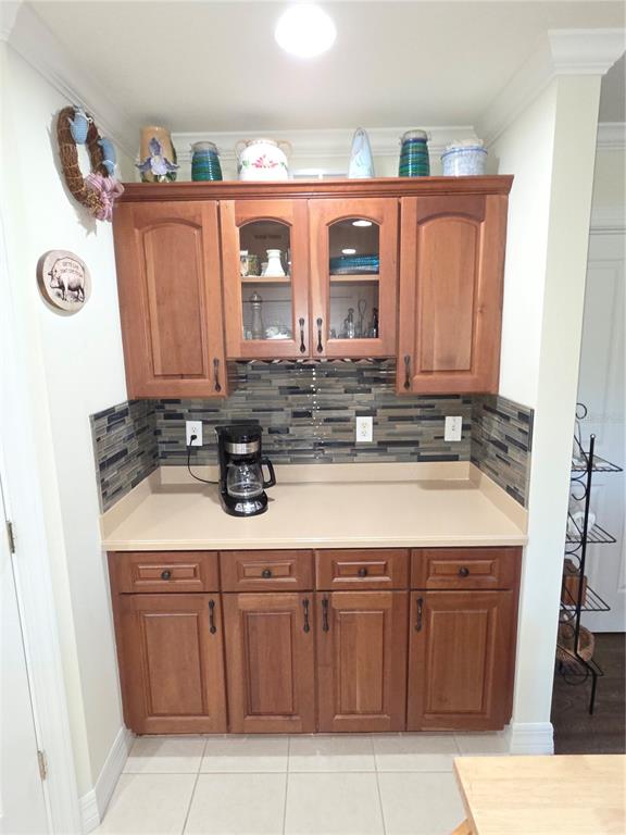 A kitchen coffee station features wood cabinets, a beige countertop, and a glass tile backsplash — 8152 SOUTHERN PINES DRIVE, BROOKSVILLE, FL
