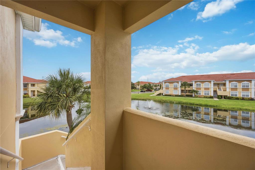 A view from a covered balcony overlooking a pond, palm tree, and apartment buildings — 1025 VILLAGIO CIRCLE UNIT 208, SARASOTA, FL