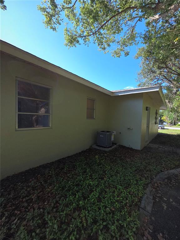 The exterior of a light-colored house features an air conditioning unit and a small window — 9091 N GOLFVIEW DRIVE, CITRUS SPRINGS, FL