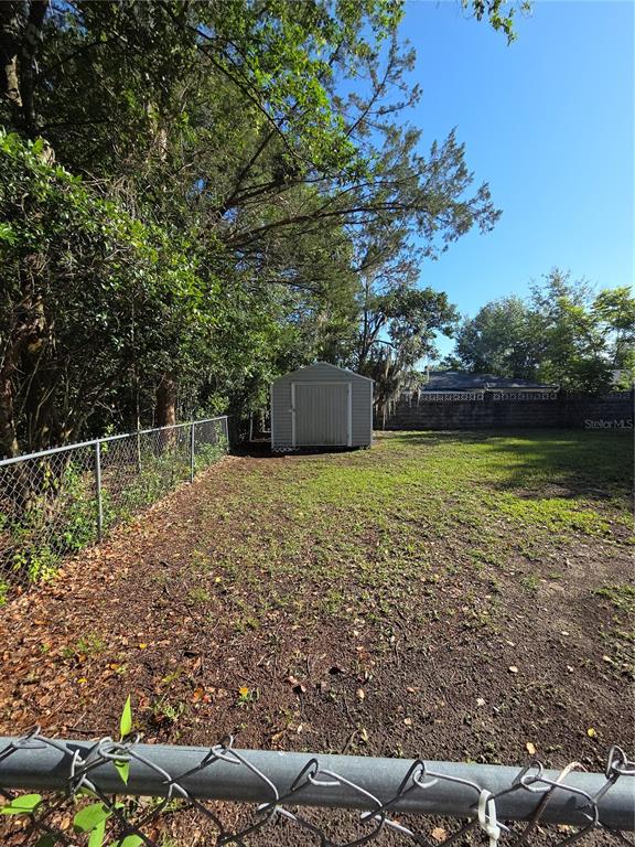 A backyard features a chain-link fence, a small storage shed, and mature trees — 9091 N GOLFVIEW DRIVE, CITRUS SPRINGS, FL
