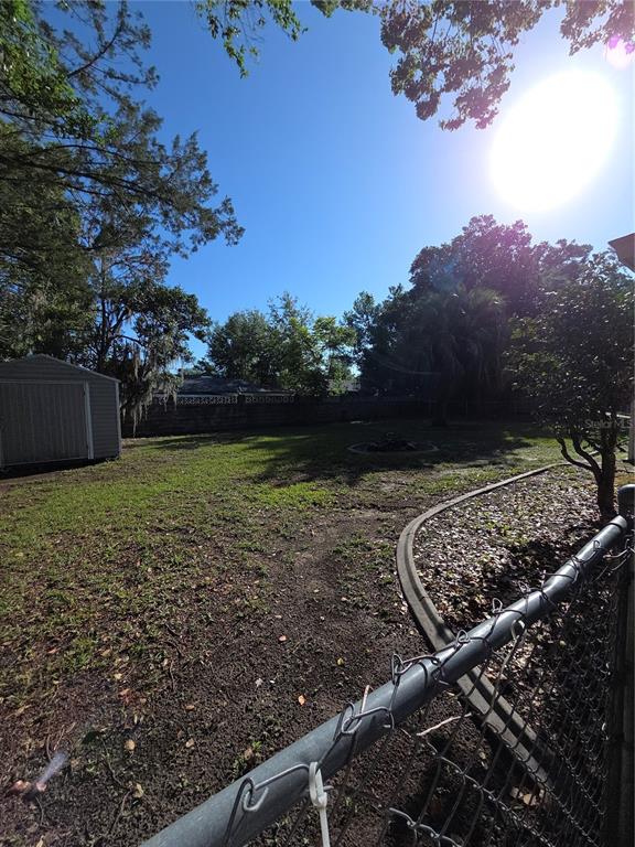 A fenced backyard features a storage shed, a fire pit, and mature trees — 9091 N GOLFVIEW DRIVE, CITRUS SPRINGS, FL