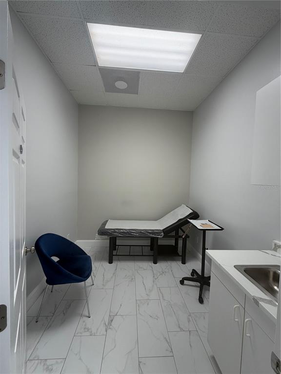 A small treatment room features a medical exam table, a blue chair, and tile flooring — 2716 REW CIRCLE, OCOEE, FL