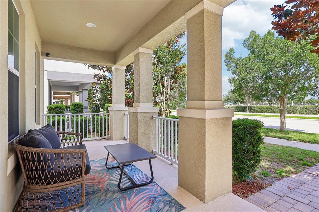 A covered front porch features a wicker sofa, a small table, and white railings — 11822 SILVERLAKE PARK DRIVE, WINDERMERE, FL