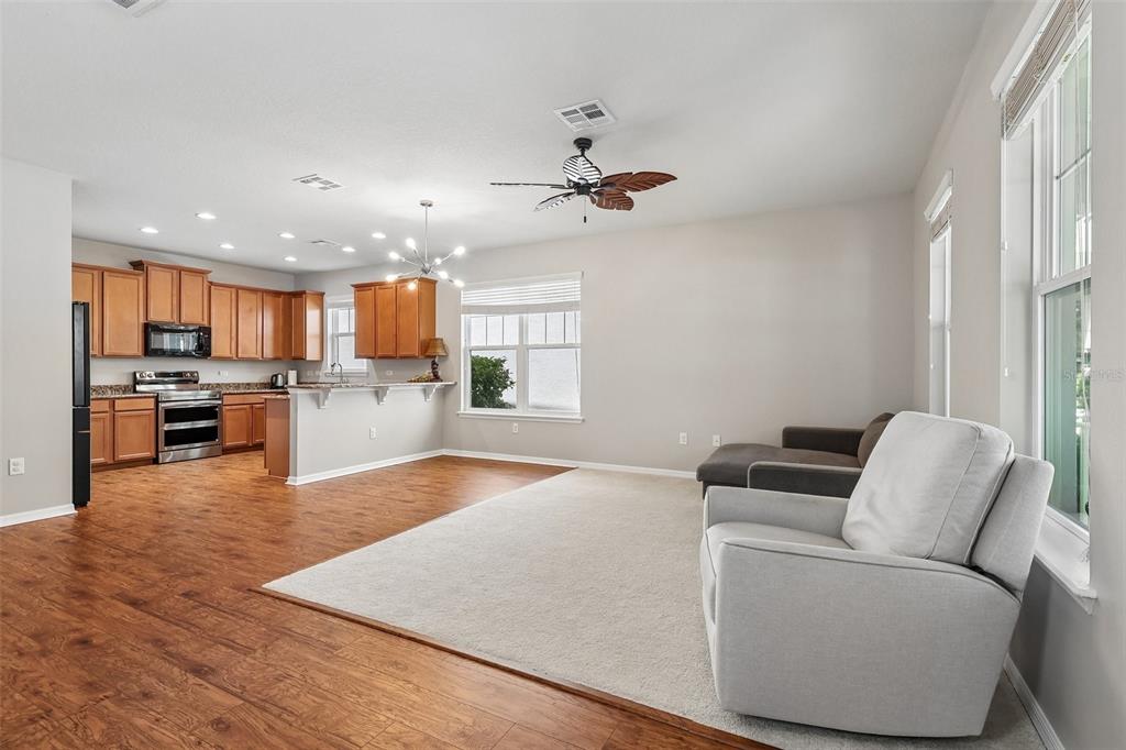 An open-concept kitchen and living area with wood flooring, carpet, and light-colored walls — 11822 SILVERLAKE PARK DRIVE, WINDERMERE, FL