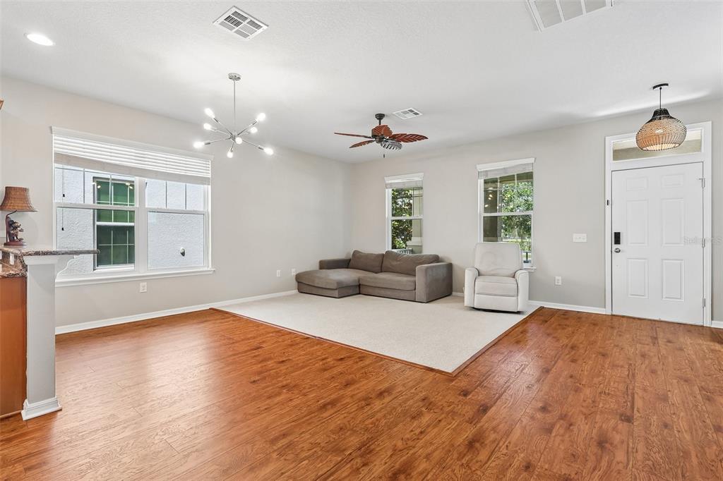 A living room with wood-look flooring, a beige area rug, a sofa, and a recliner — 11822 SILVERLAKE PARK DRIVE, WINDERMERE, FL