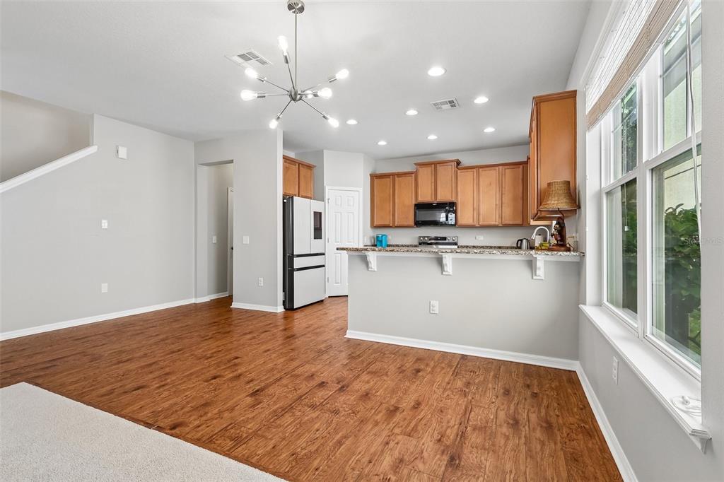 A kitchen with wood cabinets, granite countertops, and a breakfast bar overlooks a dining area — 11822 SILVERLAKE PARK DRIVE, WINDERMERE, FL