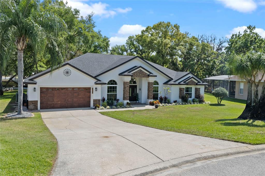 A single-story house with a white exterior, stone accents, and a two-car garage — 11516 LYONS COURT, CLERMONT, FL