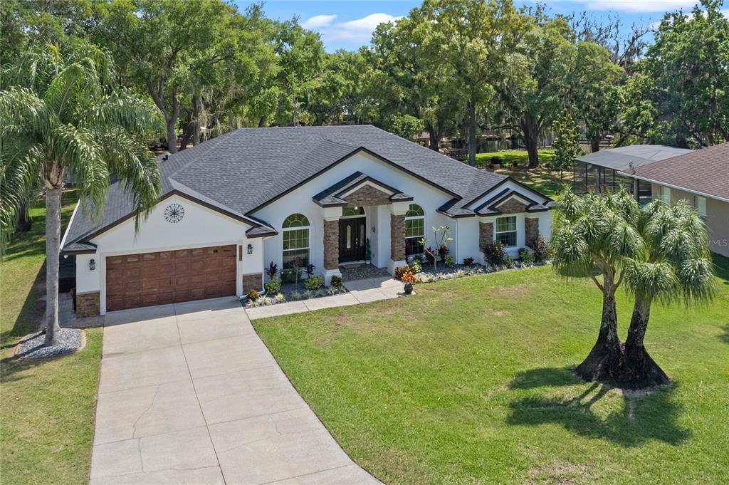 A single-story house with a white exterior, stone accents, and a two-car garage — 11516 LYONS COURT, CLERMONT, FL