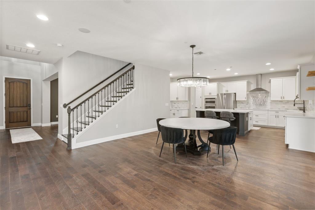 A dining area with a round table and staircase sits adjacent to an open kitchen — 8507 GEDDES LOOP, ORLANDO, FL