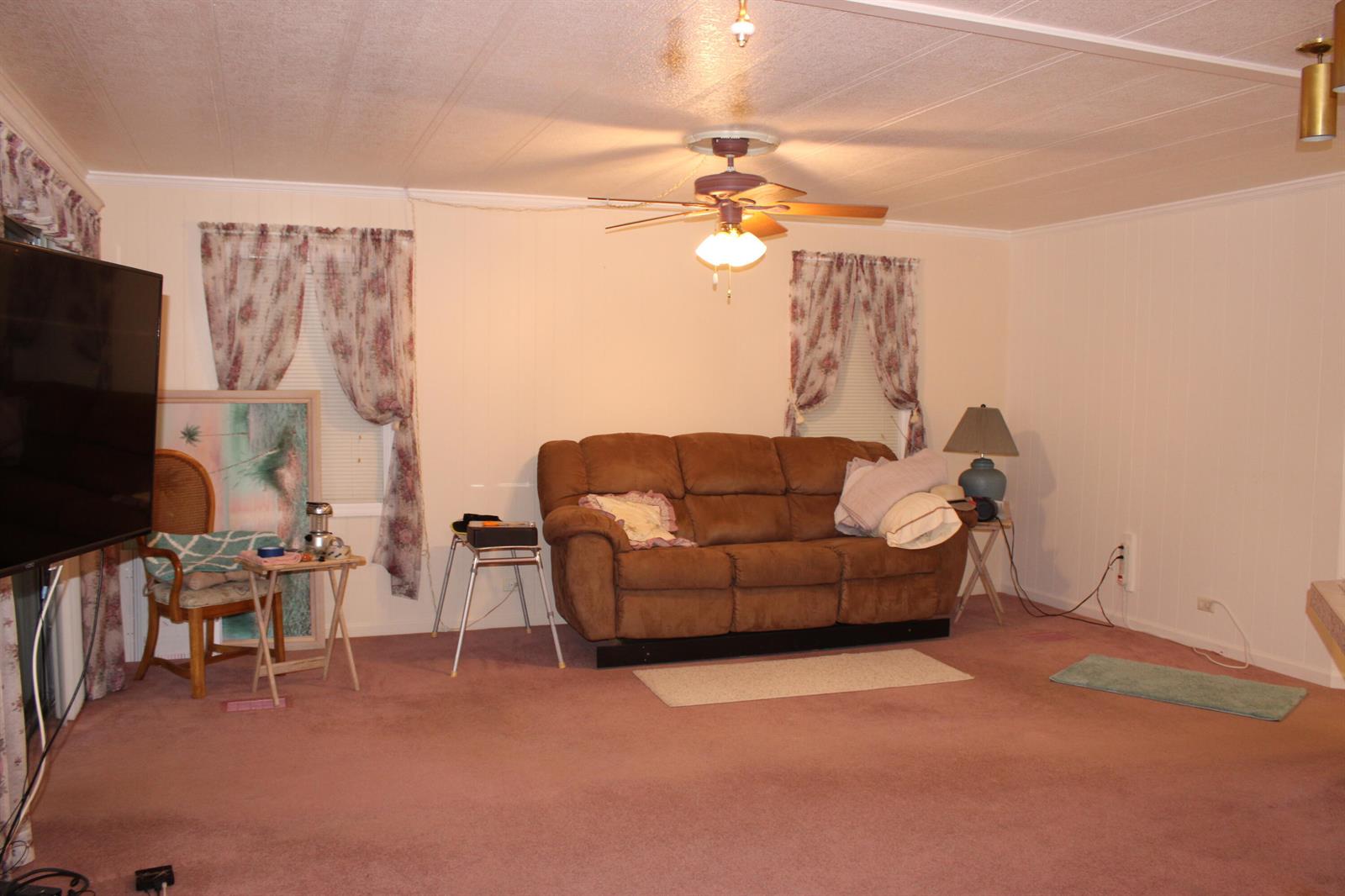 A living room features a brown sofa, pink carpeting, floral curtains, and a ceiling fan — 37010 Exuma Bay, Boynton Beach FL 33436, BOYNTON BEACH, FL