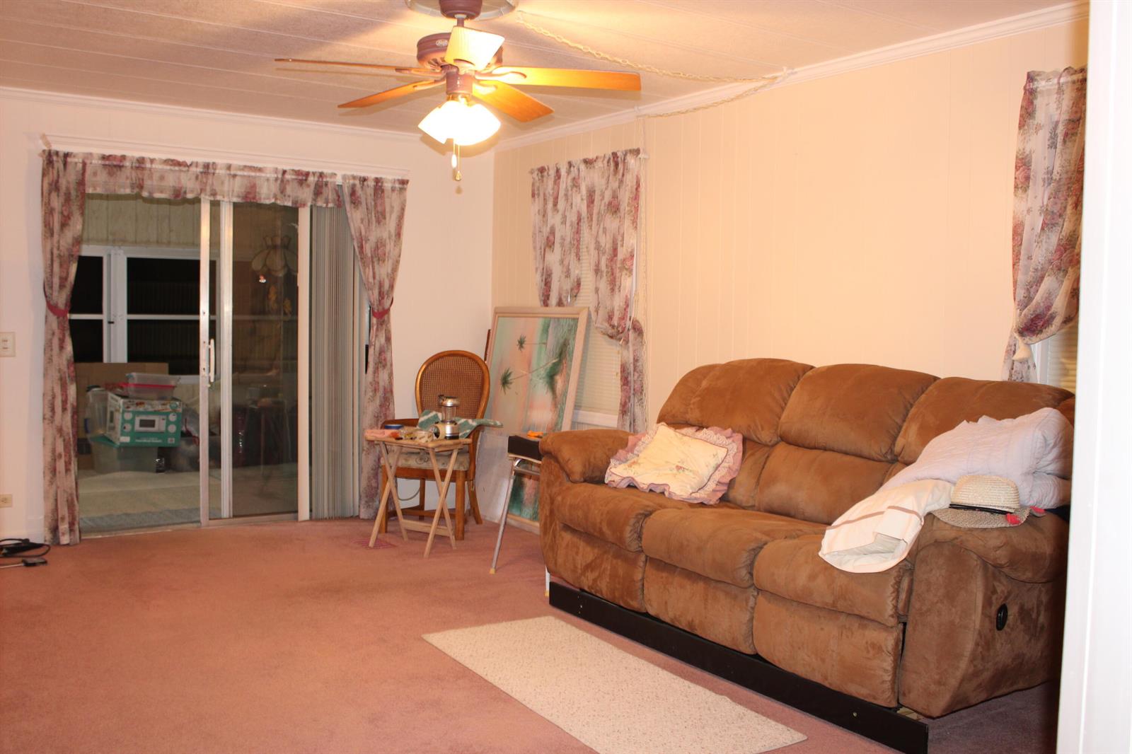 A living room features a brown reclining sofa, pink carpeting, and a ceiling fan — 37010 Exuma Bay, Boynton Beach FL 33436, BOYNTON BEACH, FL