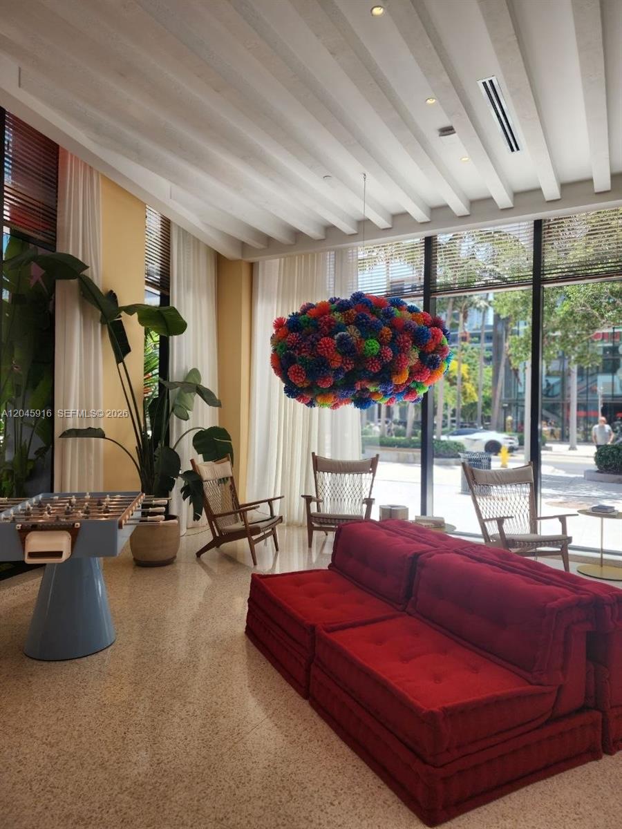 A bright lounge features a red sofa, a foosball table, and a colorful pom-pom chandelier — 90 NE 32nd # 511, Miami FL 33127, MIAMI, FL