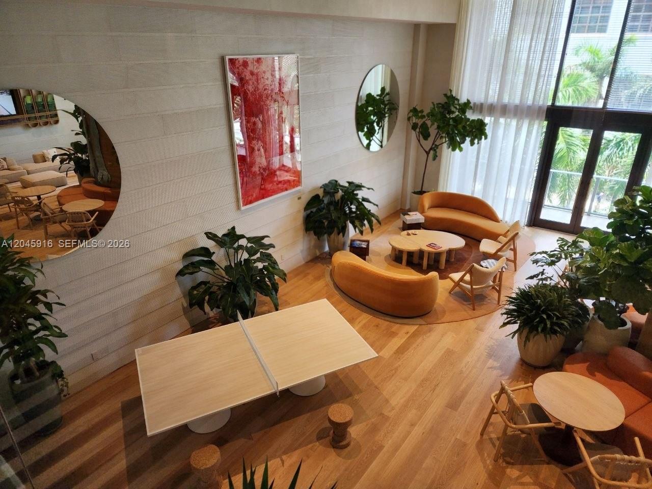 A high-ceilinged lounge area features a ping pong table, curved sofas, and large circular mirrors — 90 NE 32nd # 511, Miami FL 33127, MIAMI, FL