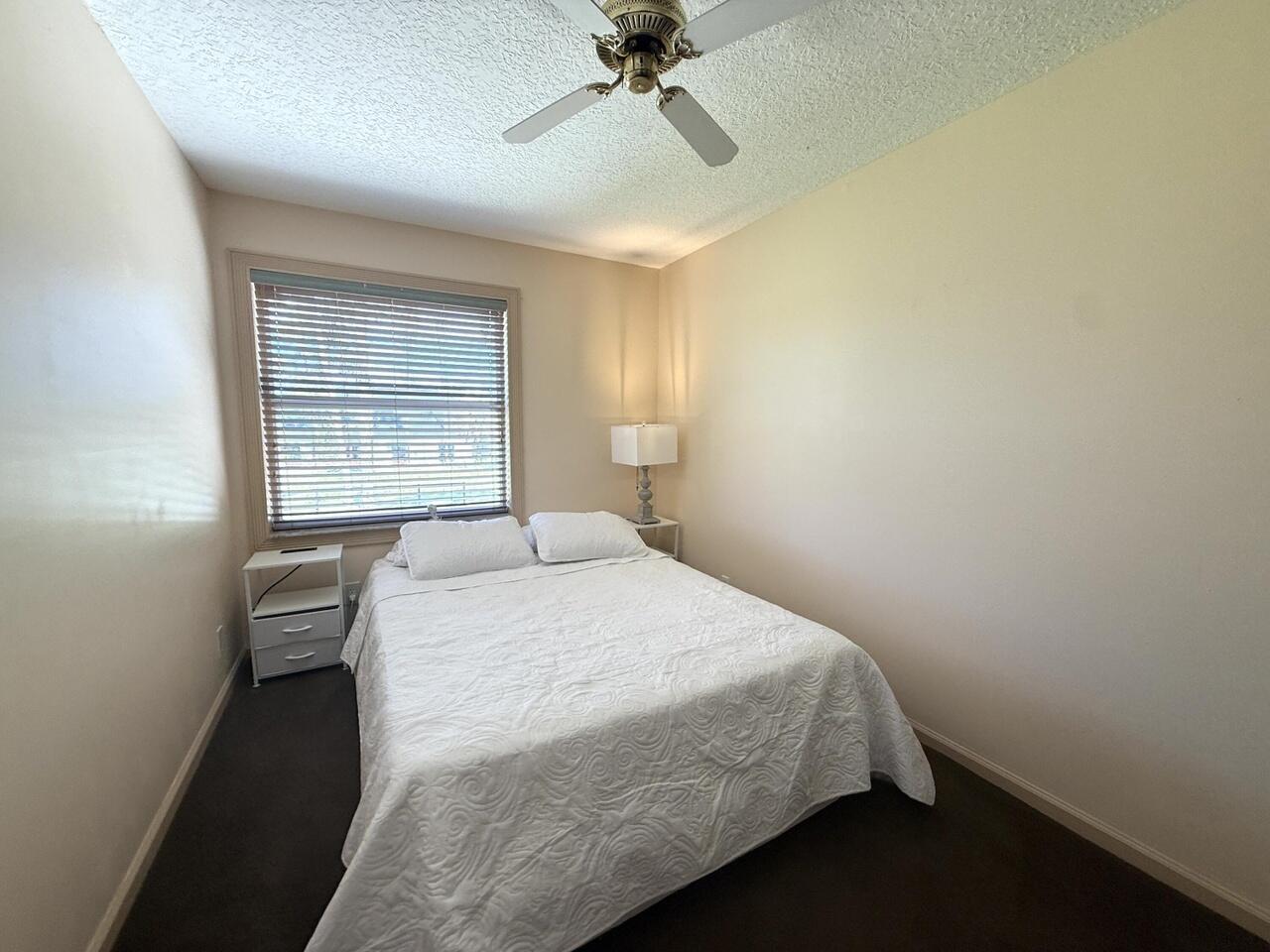 A bedroom features a bed with white bedding, two nightstands, a window, and a ceiling fan — 14765 Northlake Boulevard, FL 33412, FL