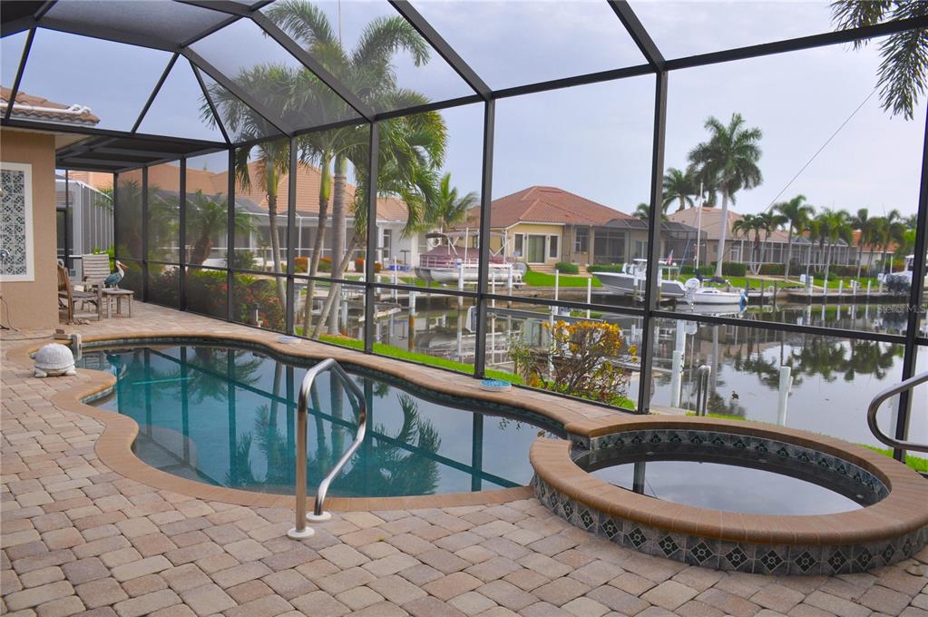 A screened-in patio features a swimming pool, a raised spa, and a view of water — 3293 TRIPOLI BOULEVARD, PUNTA GORDA, FL