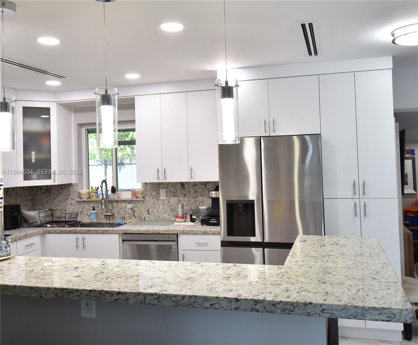A kitchen features white cabinets, granite countertops, stainless steel appliances, and two hanging pendant lights — 630 N 66th Ave, Hollywood FL 33024, HOLLYWOOD, FL