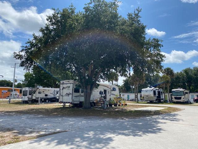 Several recreational vehicles are parked in a sunny, tree-lined lot with a concrete driveway — 8680 Us Highway 441, Okeechobee FL 34974, OKEECHOBEE, FL
