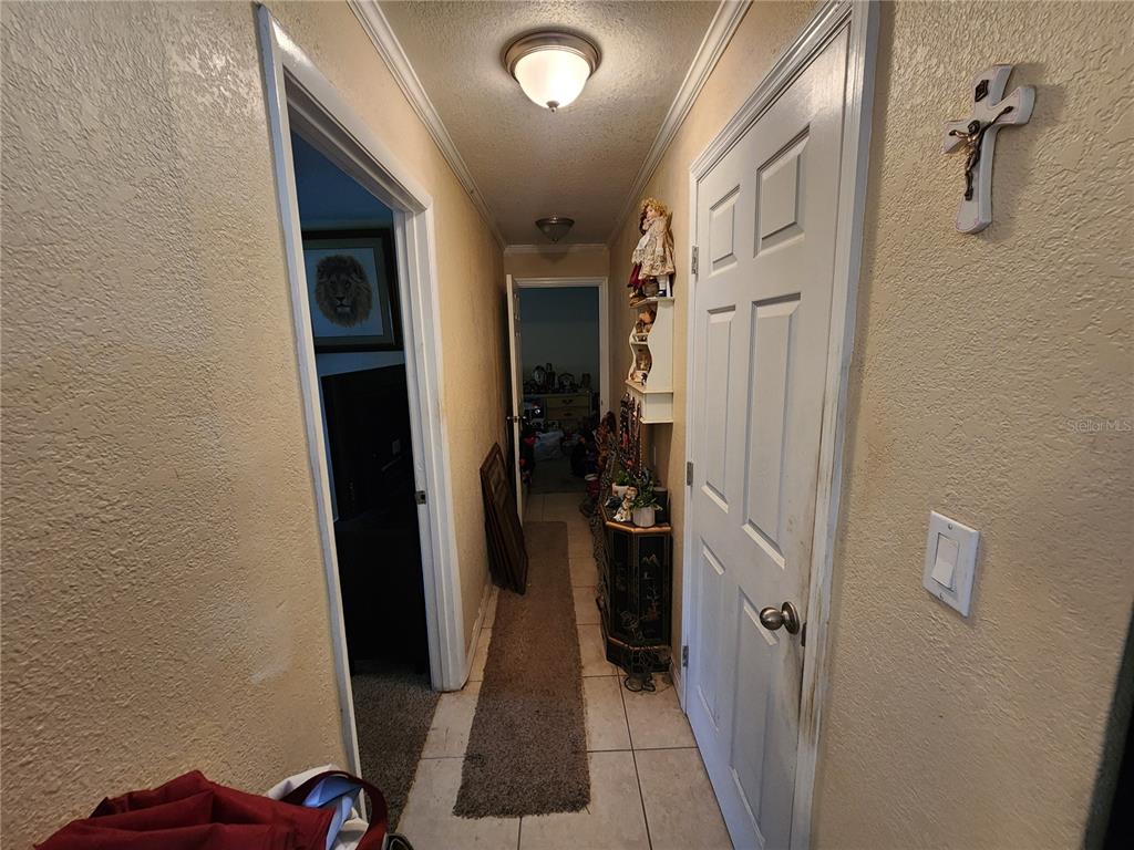 A hallway with tile flooring, a white door, and a wall-mounted crucifix — 1710 MINNIE STREET, COCOA, FL