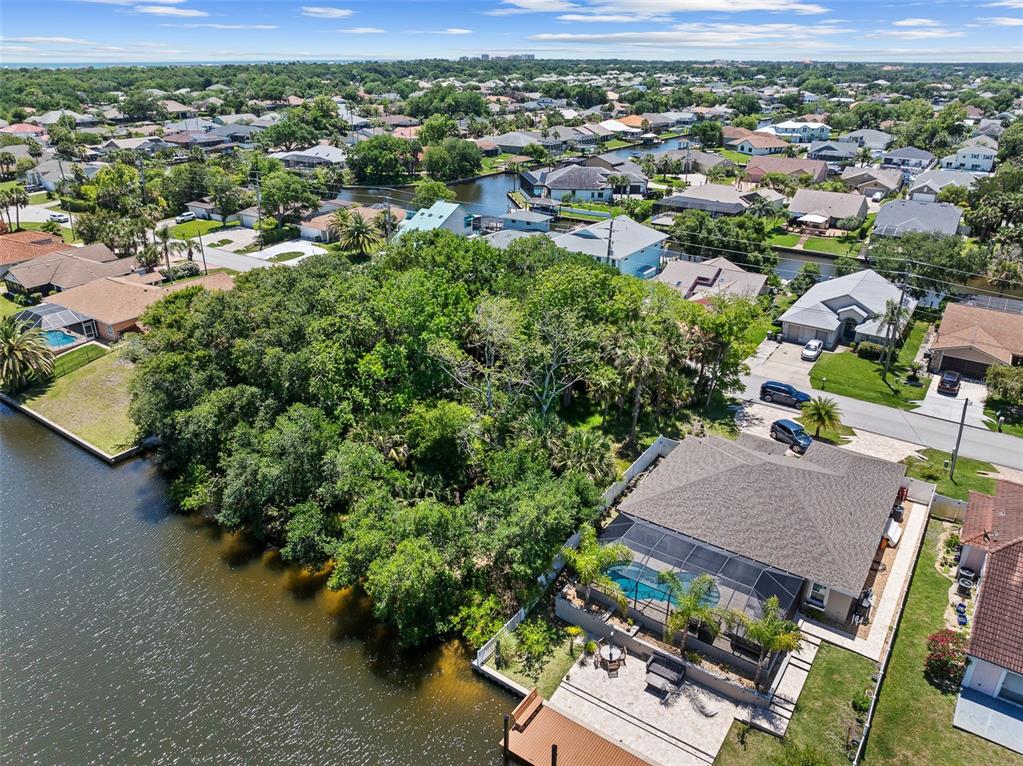 An aerial view shows a waterfront house with a pool and a large wooded lot — 111 CIMMARON DRIVE, PALM COAST, FL