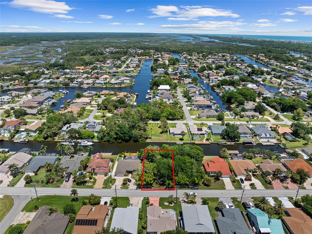 An aerial view shows a vacant, wooded residential lot outlined in red along a canal — 111 CIMMARON DRIVE, PALM COAST, FL