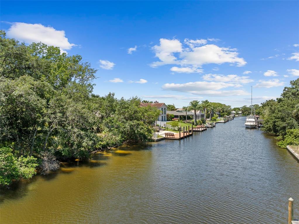 A view of a narrow canal lined with trees, private docks, and waterfront homes — 111 CIMMARON DRIVE, PALM COAST, FL