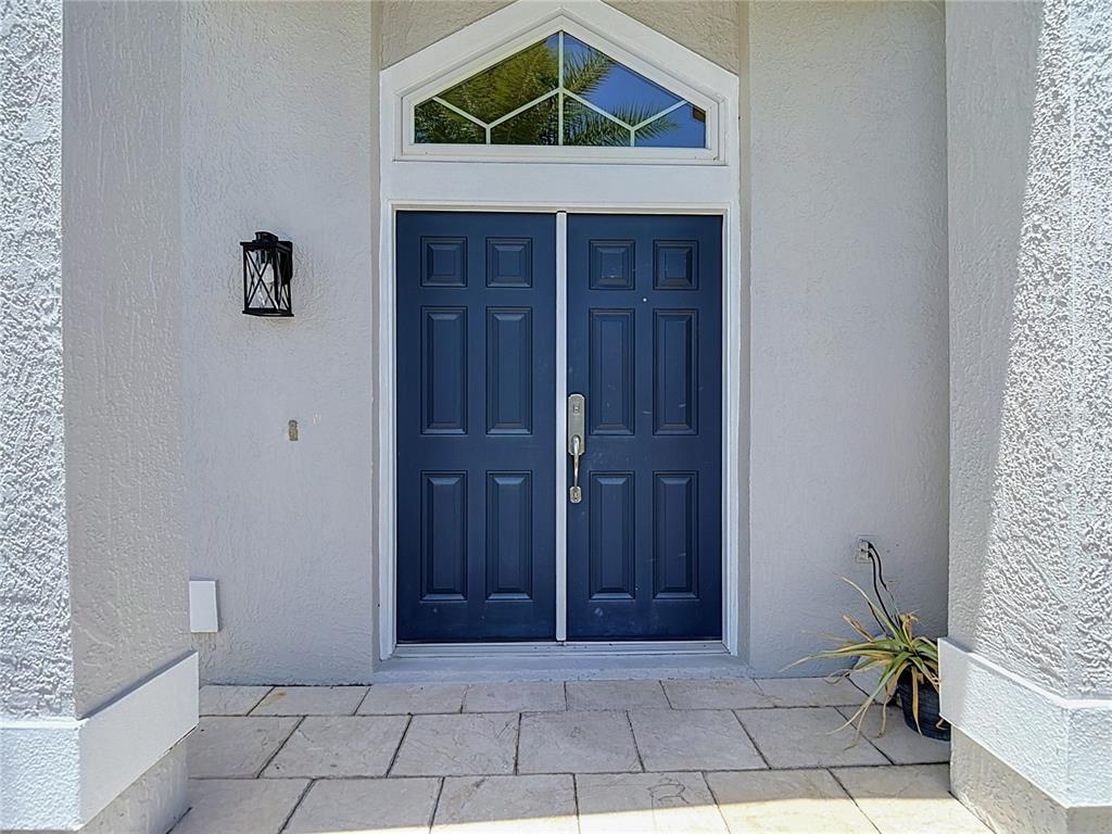 A dark blue double front door with a transom window sits on a tiled porch — 4105 ANGEL WING COURT, LUTZ, FL