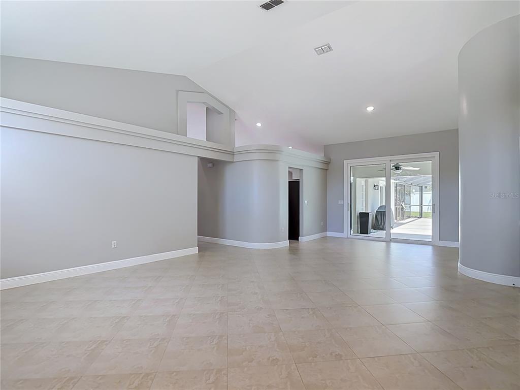 A spacious living area features light gray walls, tile flooring, and sliding glass patio doors — 4105 ANGEL WING COURT, LUTZ, FL