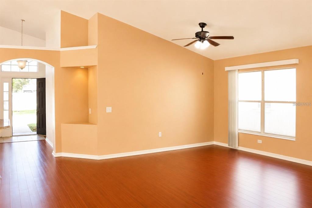 A living room with hardwood floors, a ceiling fan, and a recessed wall niche — 145 THORNBURY DRIVE, KISSIMMEE, FL