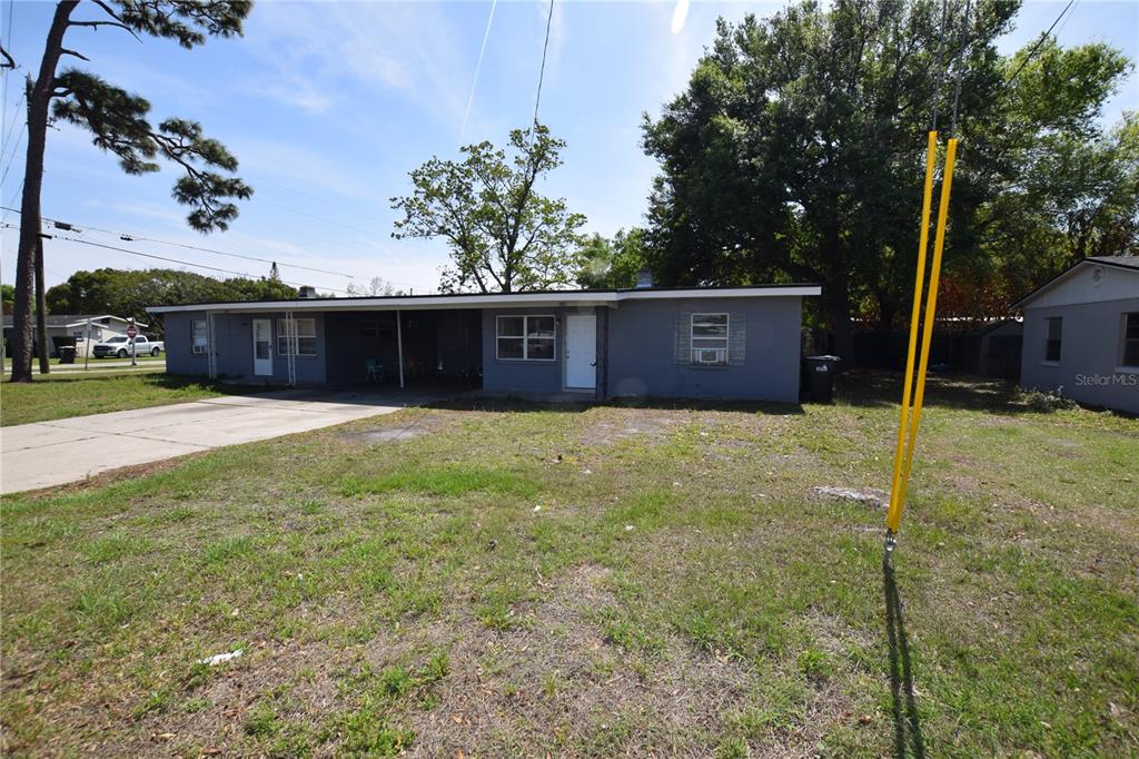 A single-story gray house with a flat roof, a carport, and a concrete driveway — 104 W LANCASTER ROAD, ORLANDO, FL