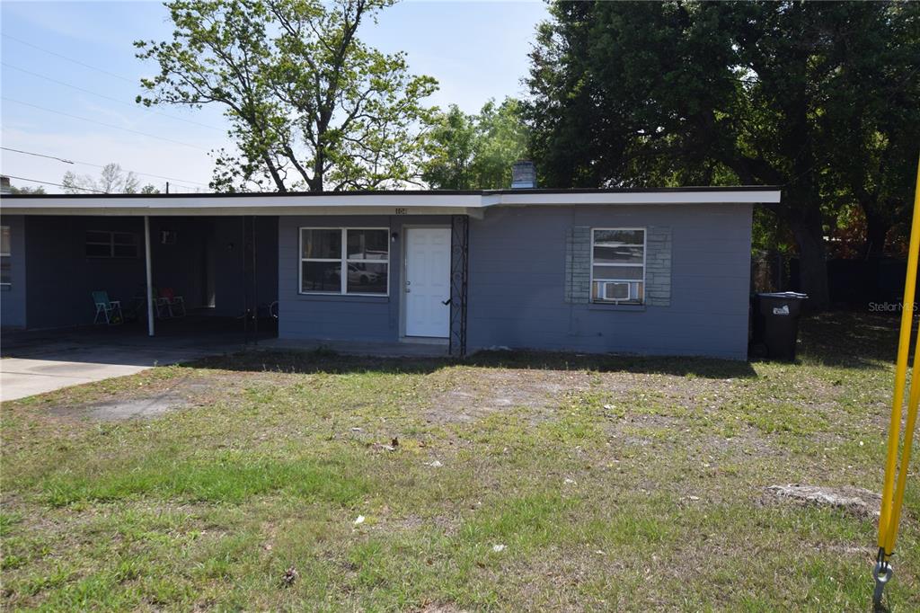 A single-story gray house with a flat roof, a carport, and a front lawn — 104 W LANCASTER ROAD, ORLANDO, FL