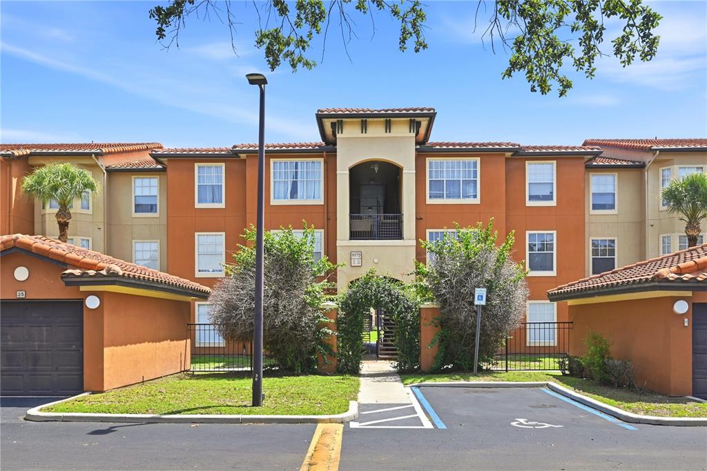 An exterior view of a multi-story apartment building with stucco walls and tile roofs — 5572 METROWEST BOULEVARD UNIT 5-304, ORLANDO, FL