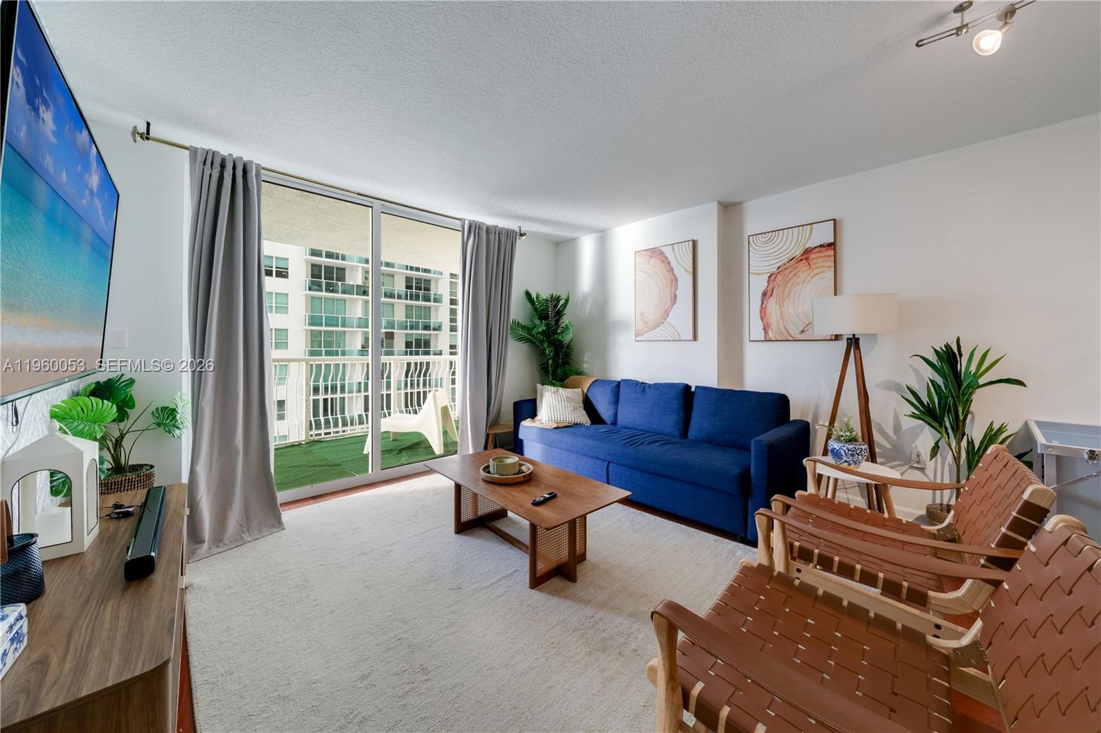 A living room features a blue sofa, two leather chairs, a coffee table, and balcony access — 1200 Brickell Bay Dr # 1705, Miami FL 33131, MIAMI, FL