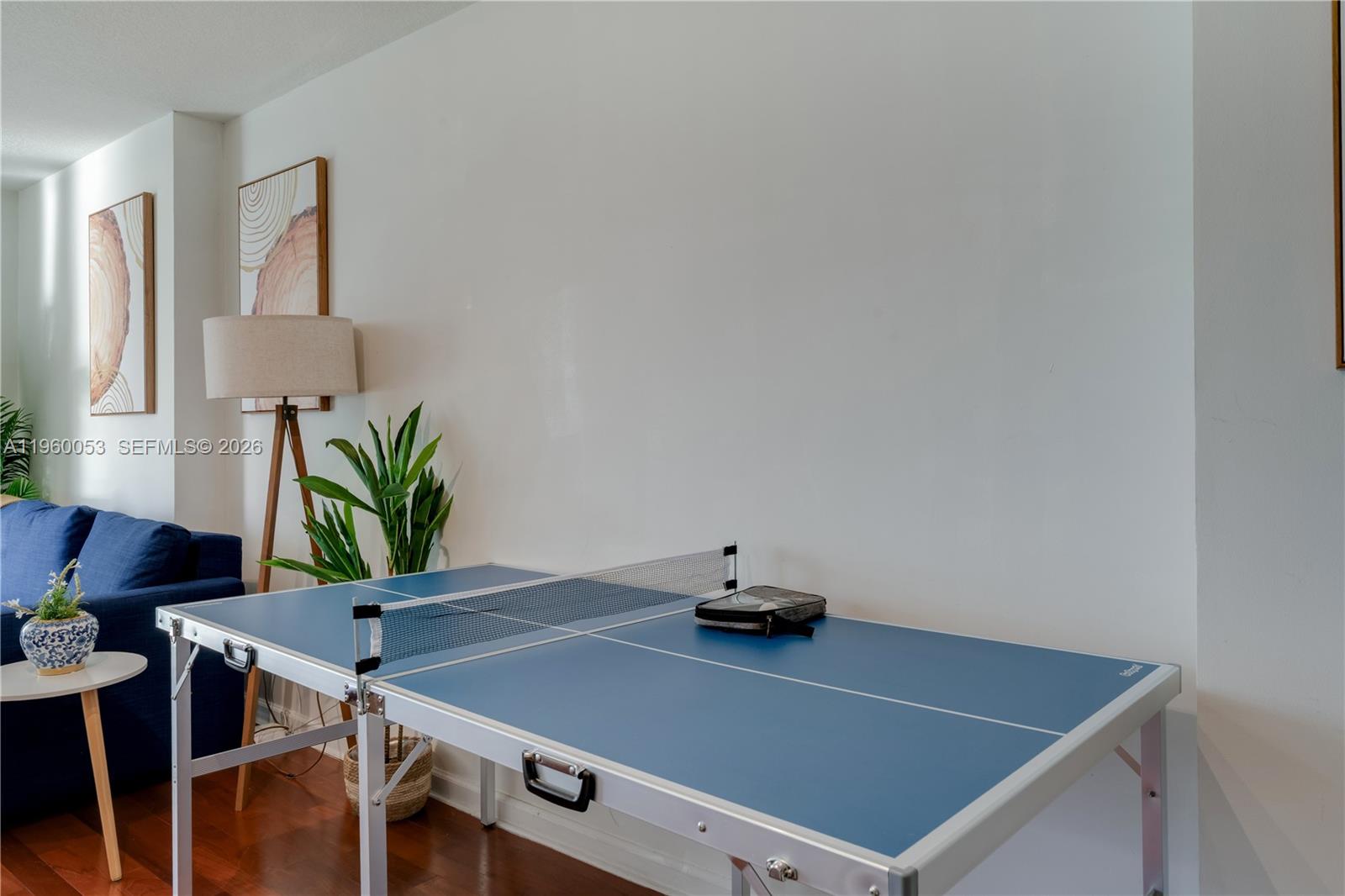 A blue ping pong table sits in a living room with hardwood floors and artwork — 1200 Brickell Bay Dr # 1705, Miami FL 33131, MIAMI, FL