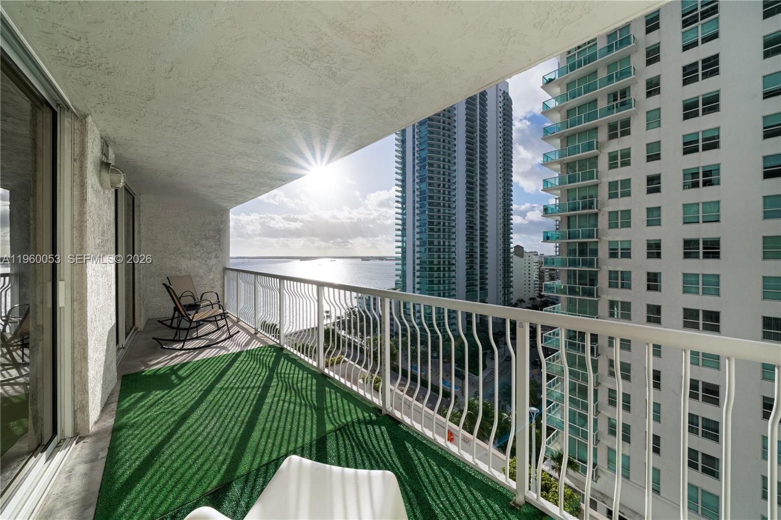 A balcony with green turf flooring overlooks a bay and neighboring high-rise buildings — 1200 Brickell Bay Dr # 1705, Miami FL 33131, MIAMI, FL