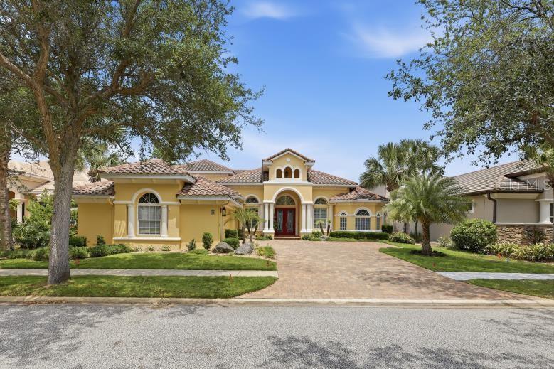 A yellow stucco house with a tiled roof and a paved driveway under a blue sky — 34 N WATERVIEW DRIVE, PALM COAST, FL