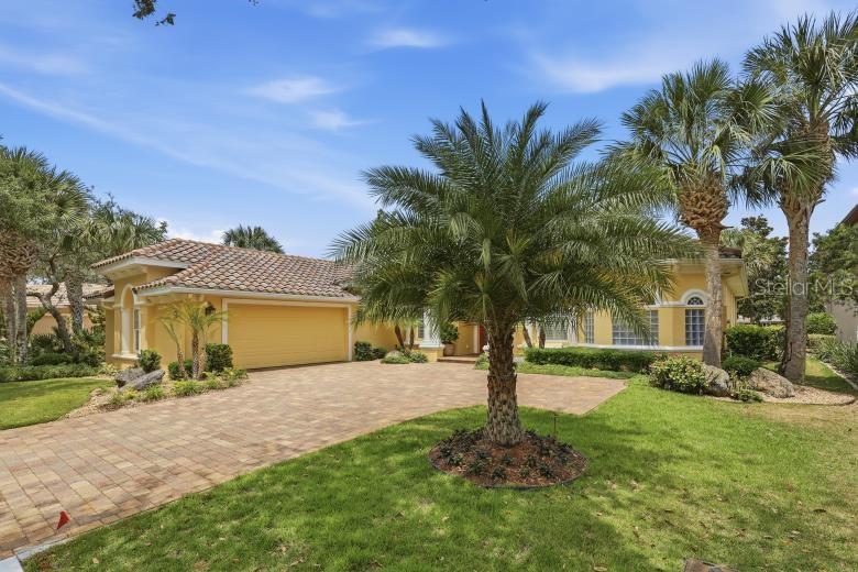 A yellow house with a tile roof, a brick driveway, and palm trees in the yard — 34 N WATERVIEW DRIVE, PALM COAST, FL