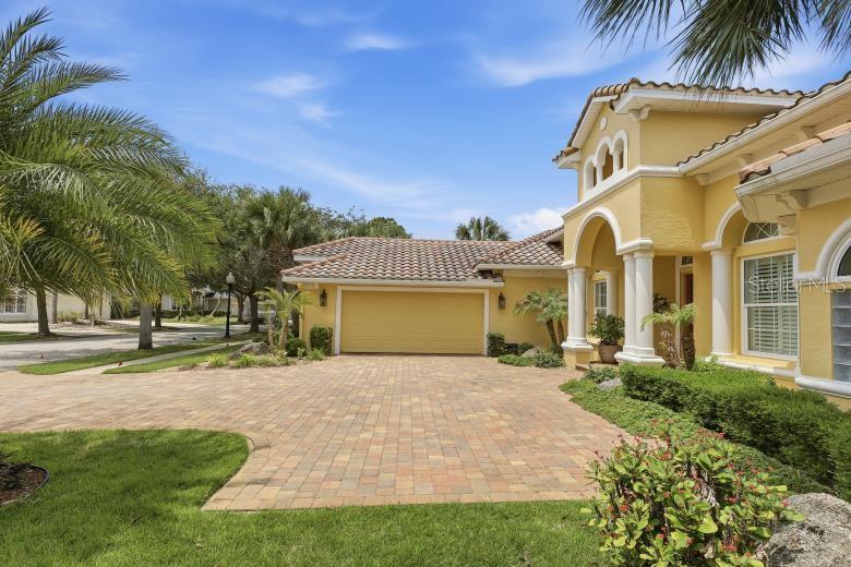 A yellow stucco house features a paved driveway, a two-car garage, and arched architectural details — 34 N WATERVIEW DRIVE, PALM COAST, FL